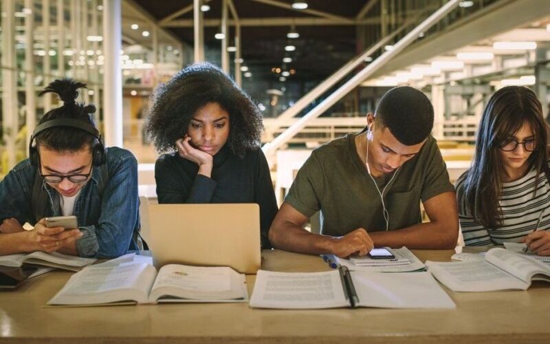 a group of people sitting at a table looking at a laptop