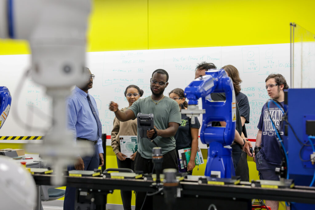A university student operates a smart factory to demonstrate manufacturing automation principles.