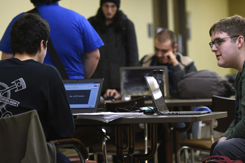 a group of people sitting at a table with laptops