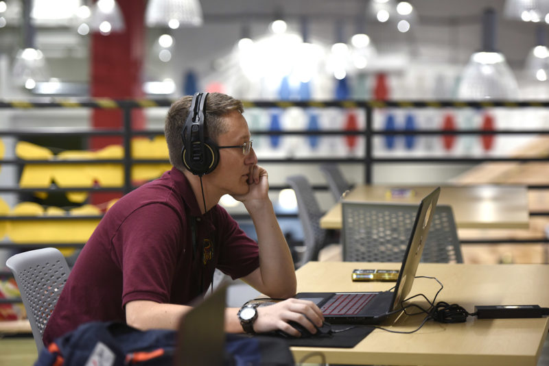 a person wearing headphones and sitting at a desk with a laptop