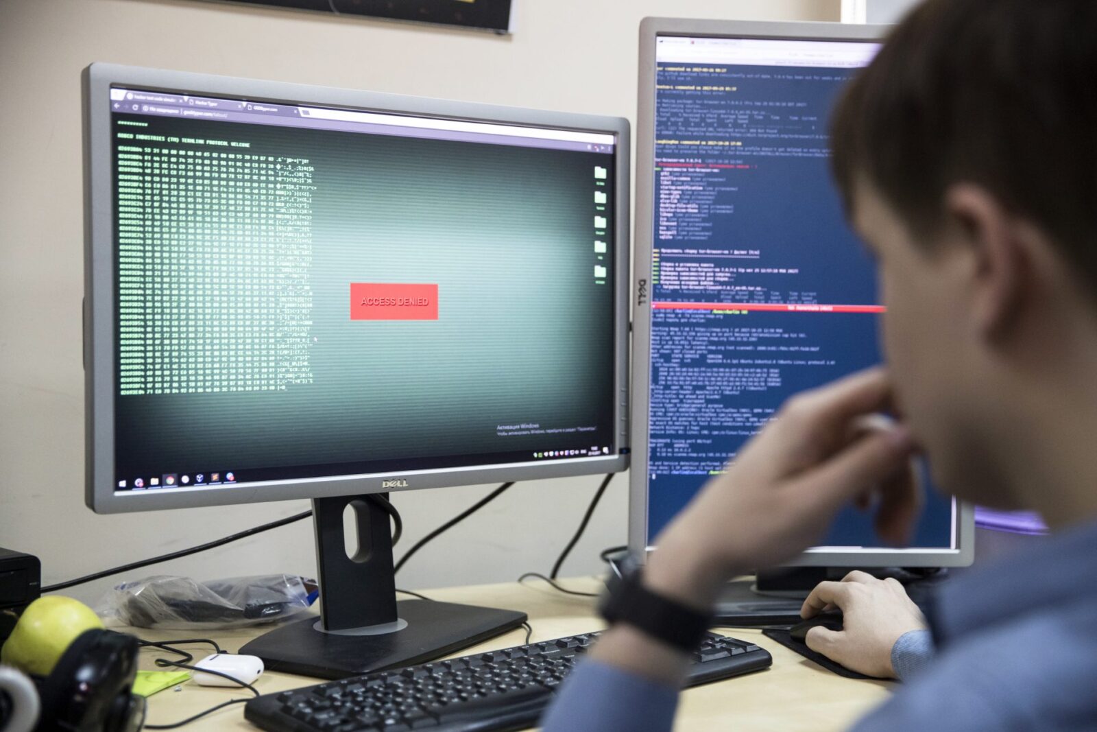 a person sitting at a desk with a computer and a monitor