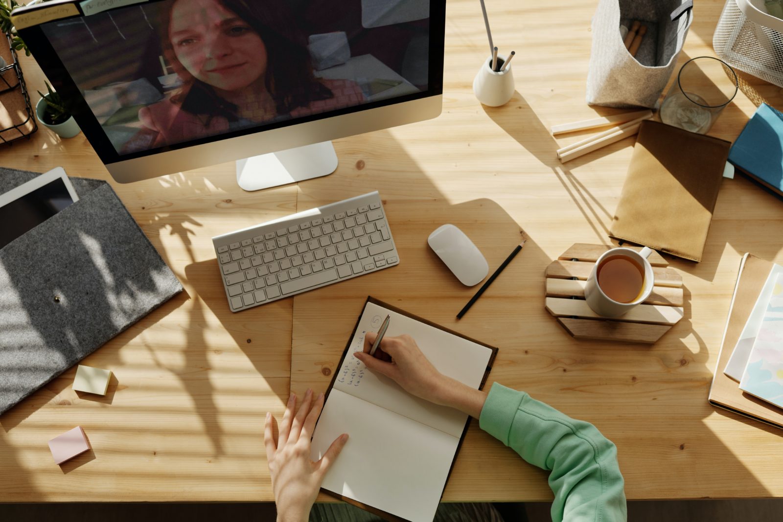 a person's hand holding a pen and paper in front of a computer screen