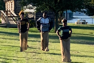 a group of people standing in a grassy area playing games